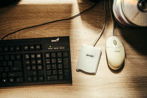 Teclado, lector de tarjeta y ratón sobre un escritorio de madera.